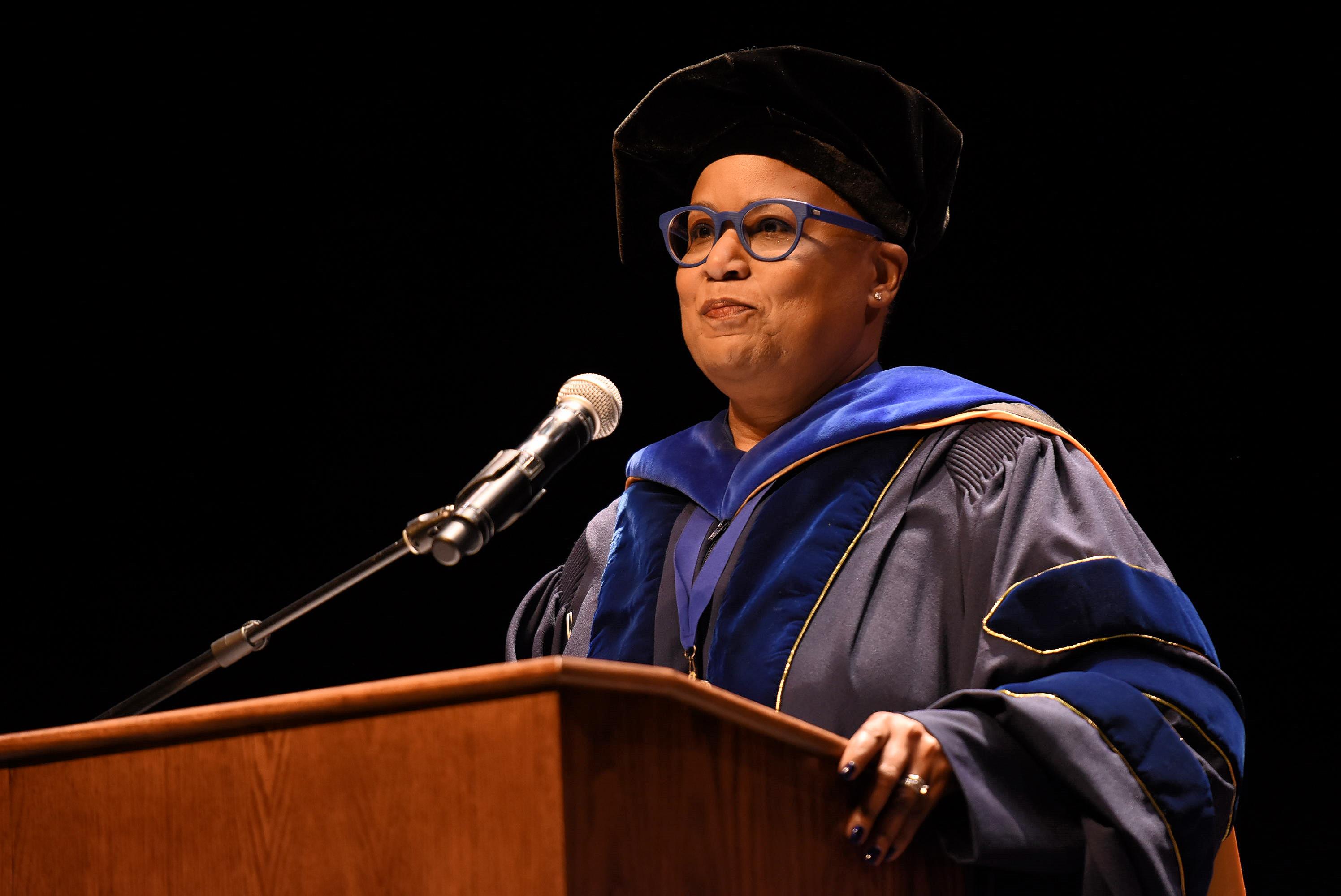Speaker at podium during commencement wearing purple glasses