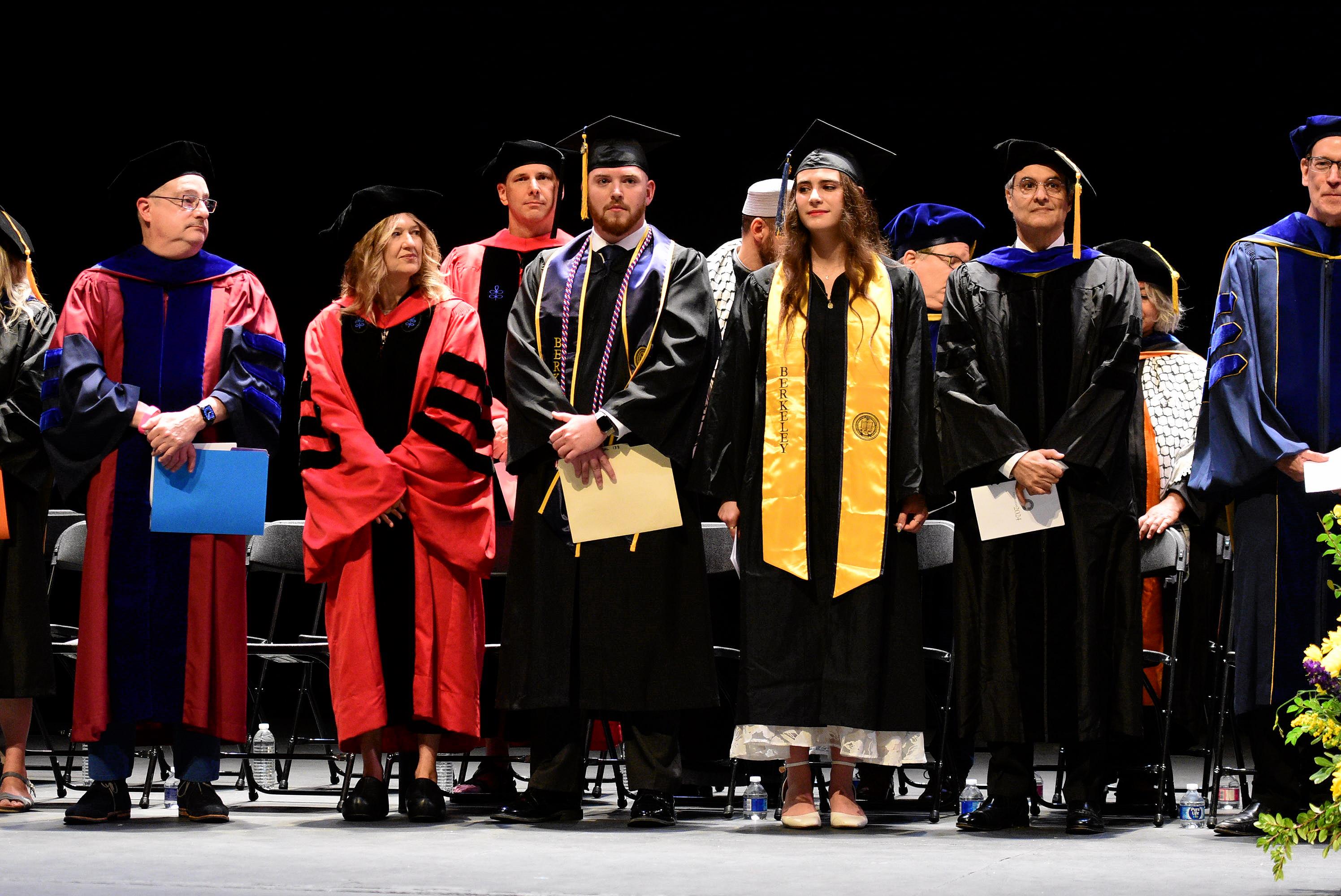 Graduates and faculty stand together at commencement