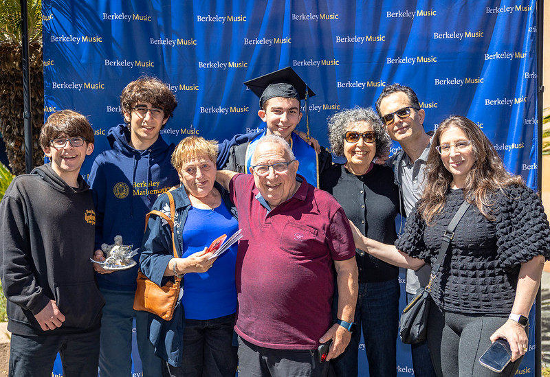 Graduate in front of Music Department blue step and repeat with loved ones