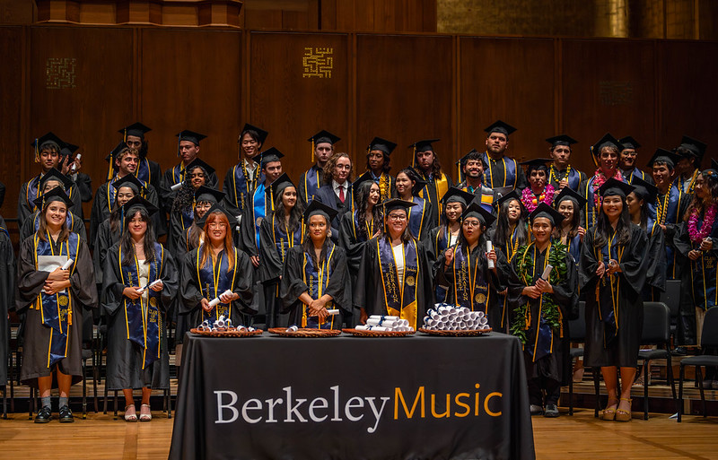 Graduates stand behind a Berkeley Music table