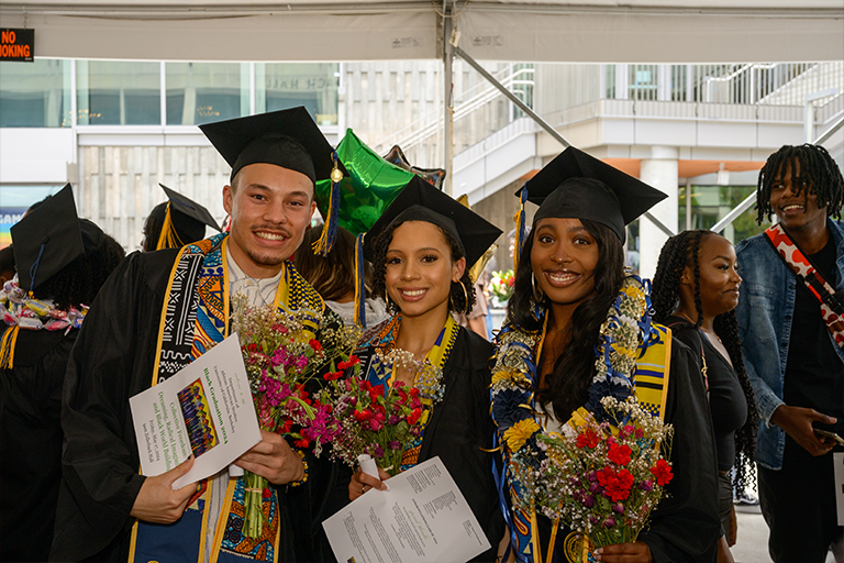 Three graduates smile at camera