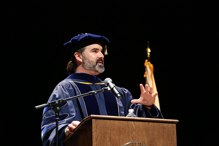 Faculty member speaks at a podium for commencement