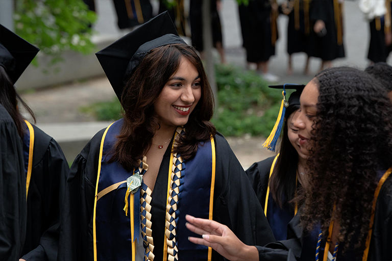 A graduate smiles while talking to her friend