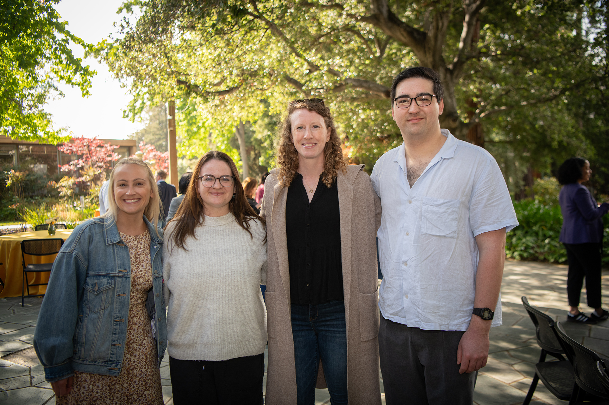 Four people stand together smiling at camera