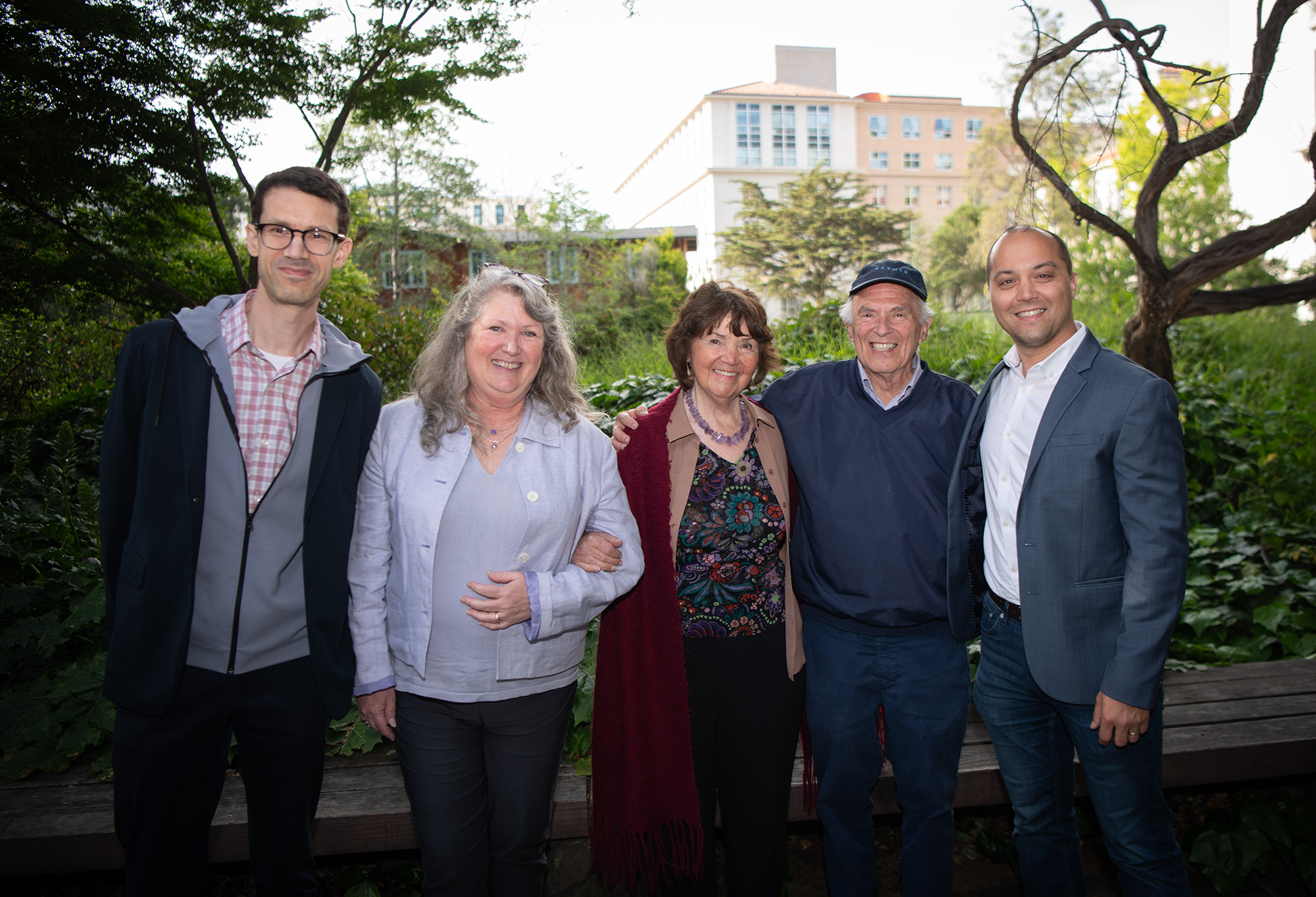 Five people stand together smiling
