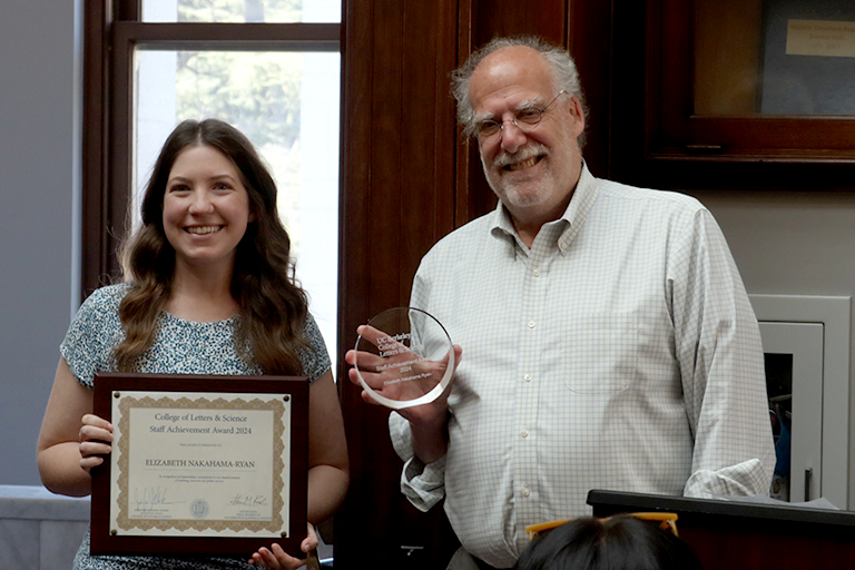 A woman and a man stand together, holding awards