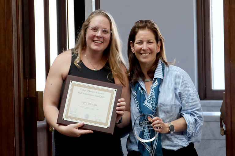 Two woman hold awards and pose together