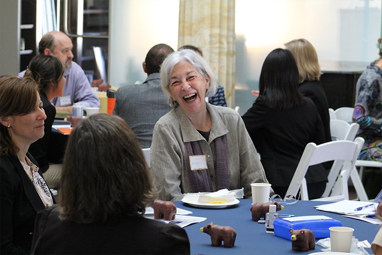 Janet Broughton laughs at table with working group