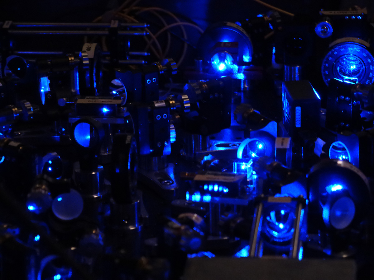 Blue laser beams move around a crowded table using lenses and mirrors