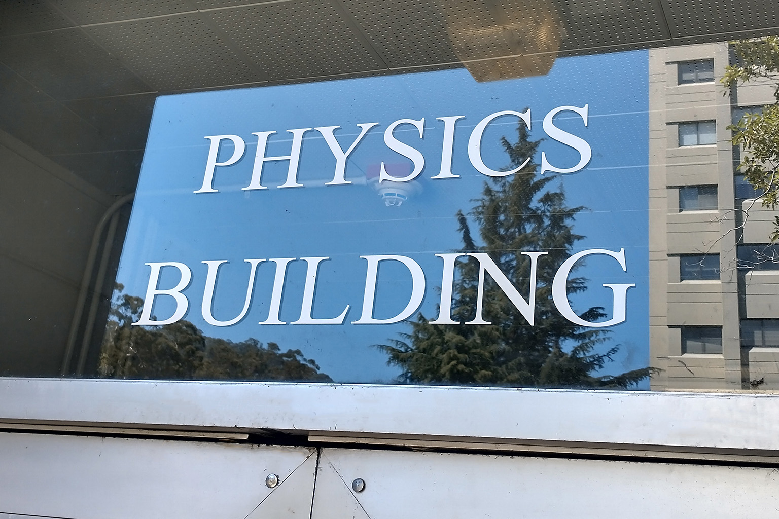 The words "PHYSICS BUILDING" are labelled on a glass window above a door.