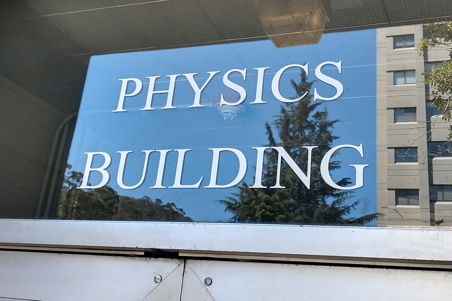 The words "PHYSICS BUILDING" are labelled on a glass window above a door.