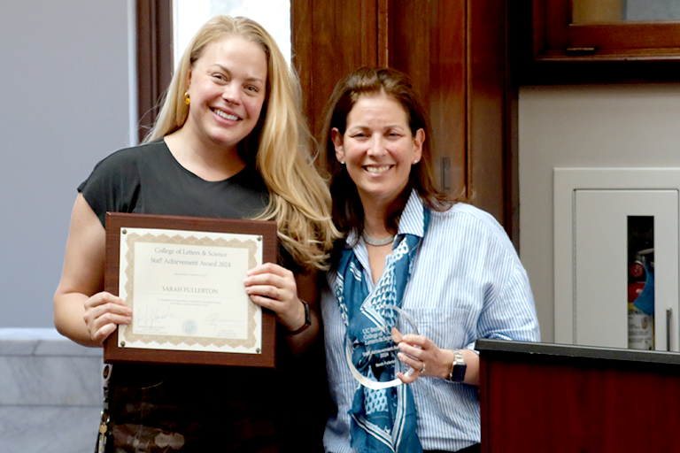 Two women hold awards and pose together