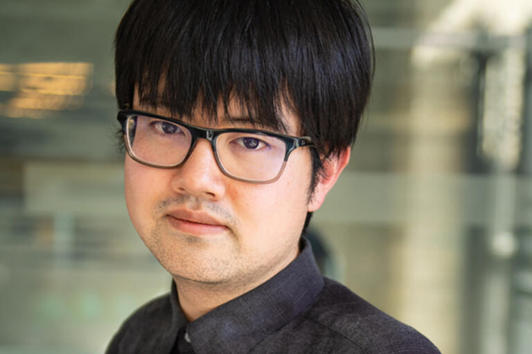 Headshot of a man with black hair, glasses, and a dark gray shirt