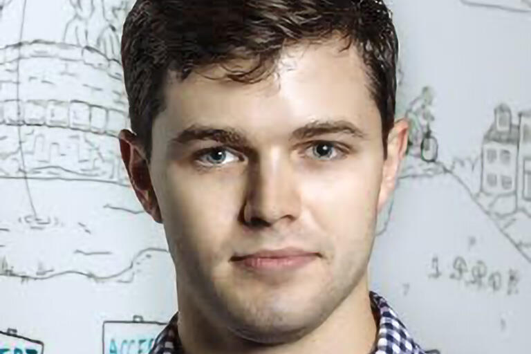A man in a blue and white checkered shirt in front of an illustration