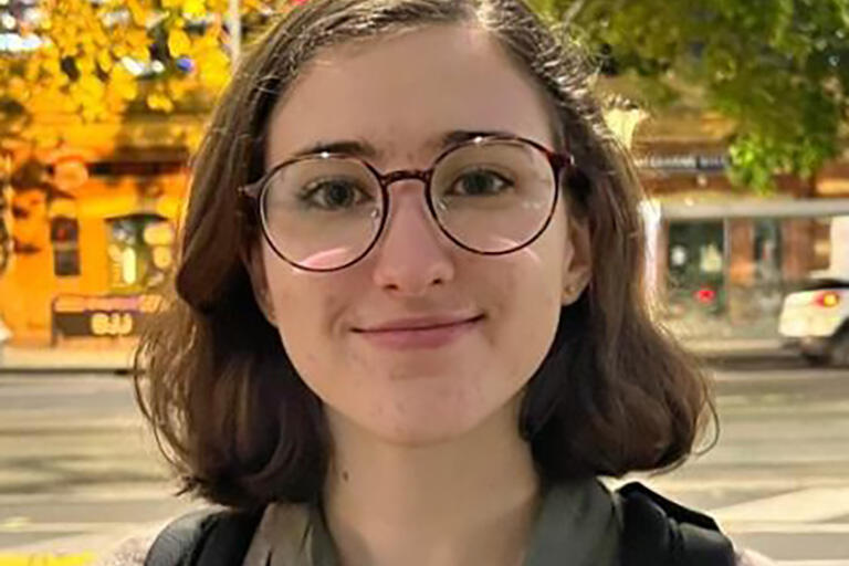 A woman with brown hair, round glasses, and a black backpack