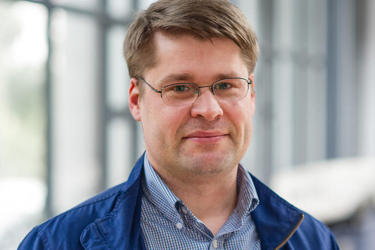 A man wearing a blue jacket over a light blue, button-down shirt