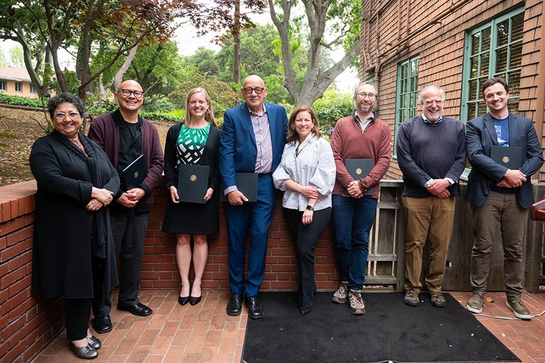 Group of faculty awardees and deans standing outside; awardees holding their awards