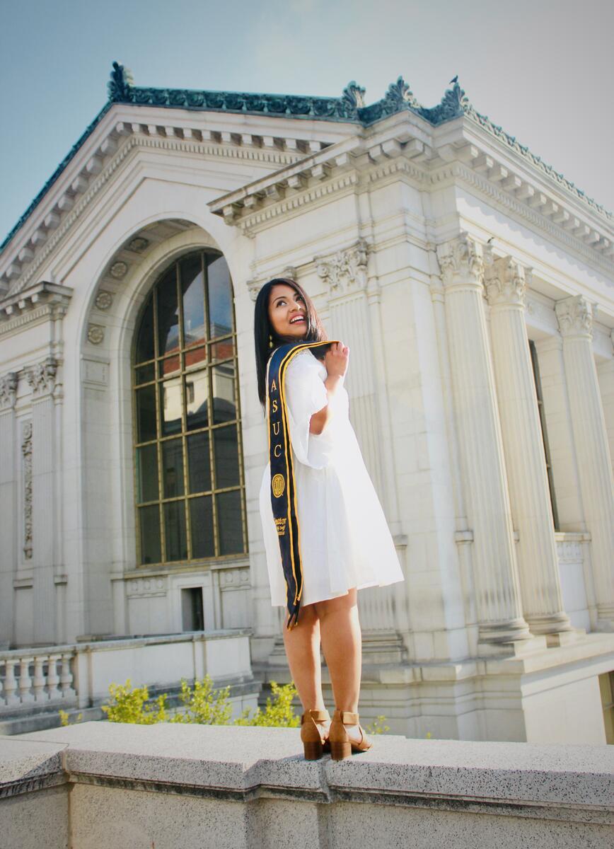 Graduate looking back over her shoulder, with the university library in the background