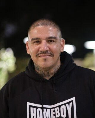 A man wears a black Homeboy Industries sweatshirt