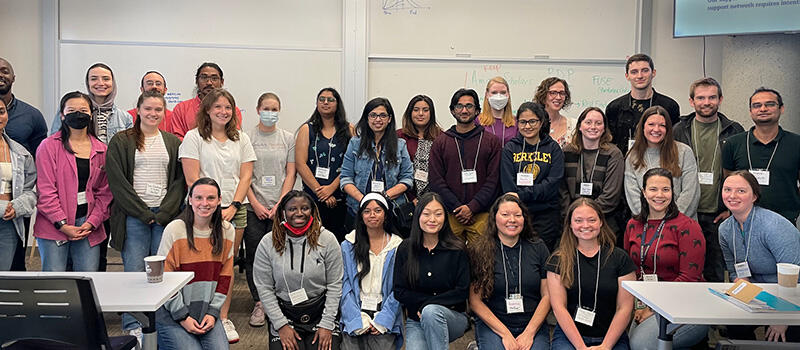 A large group of people pose for a photo in a classroom