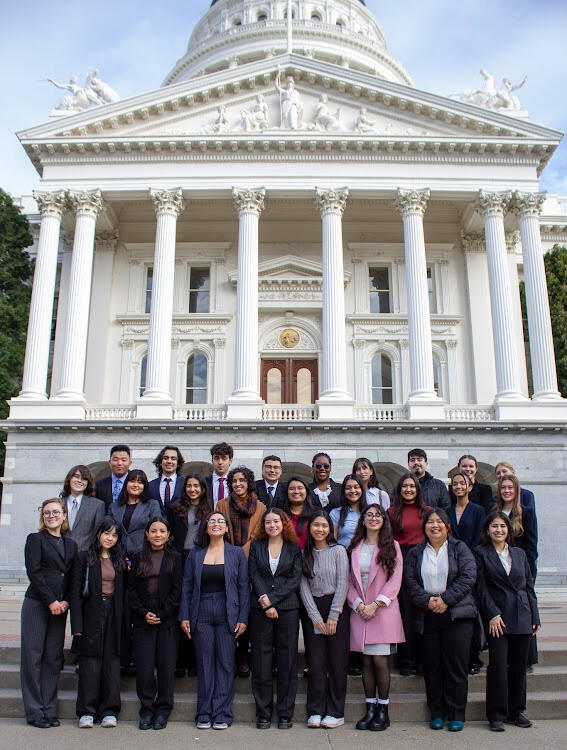 27 Cal-in-Sacramento fellows pose for a group photo in front of a large government building.
