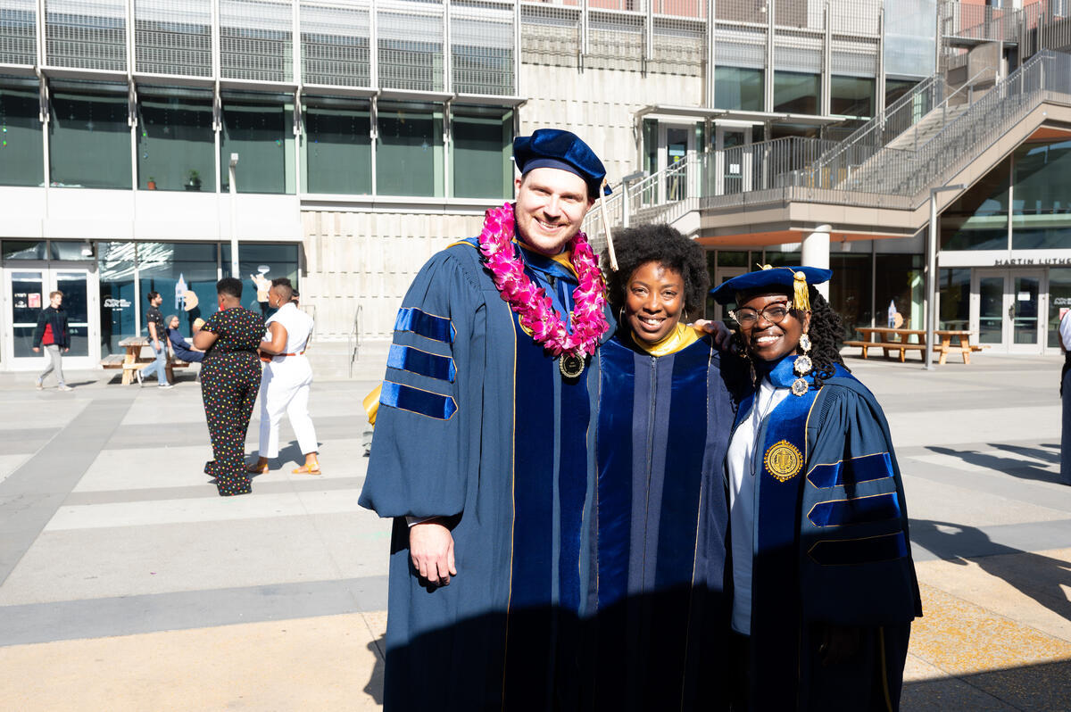 Three African American Studies graduates standing together smiling after the ceremony