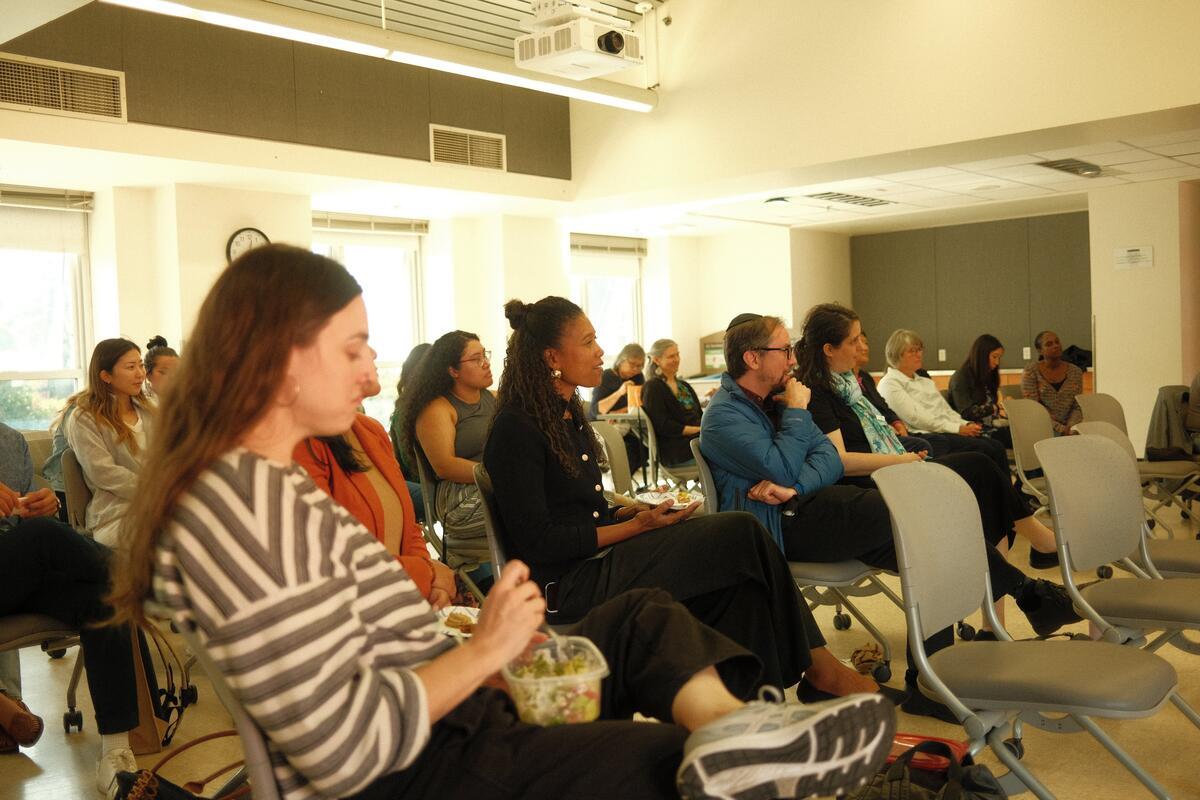 Crowd of staff in audience listen to talk.