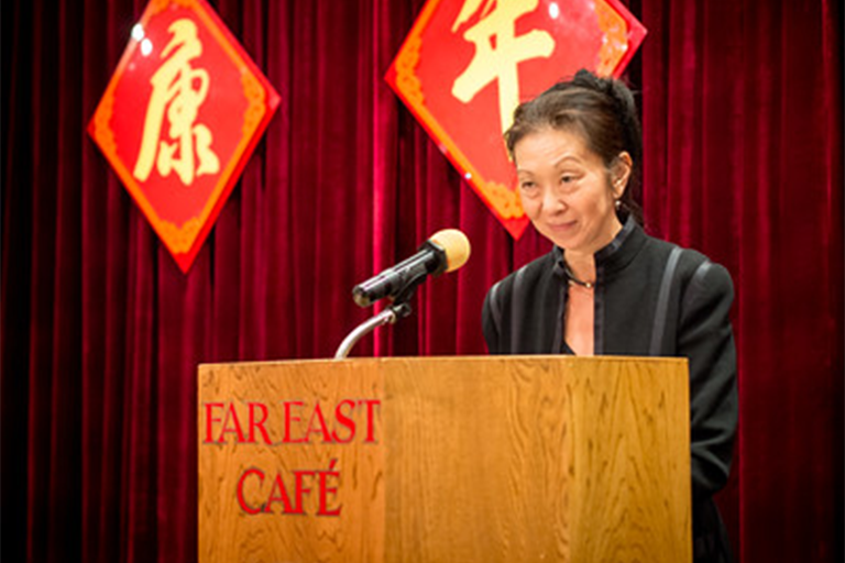 Image of Fae Myenne Ng at a podium (dark haired woman)