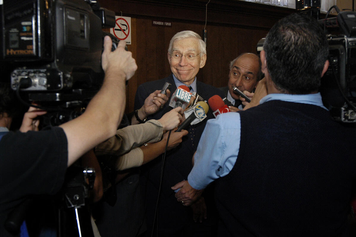 A man is surrounded by journalists with camera and microphones