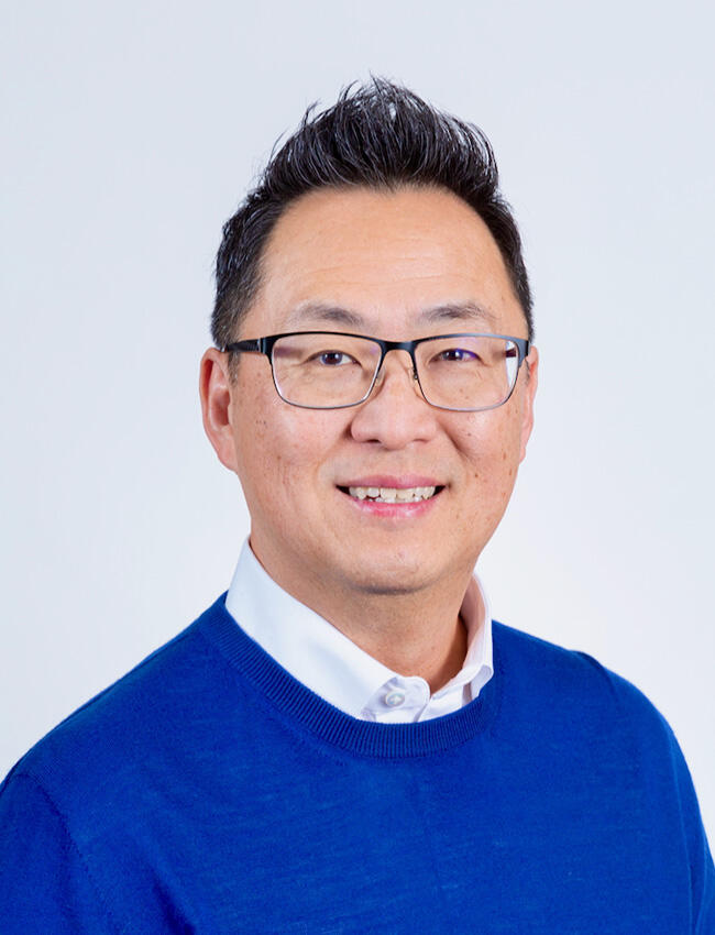 Headshot of a man with short, raised hair and a blue sweater