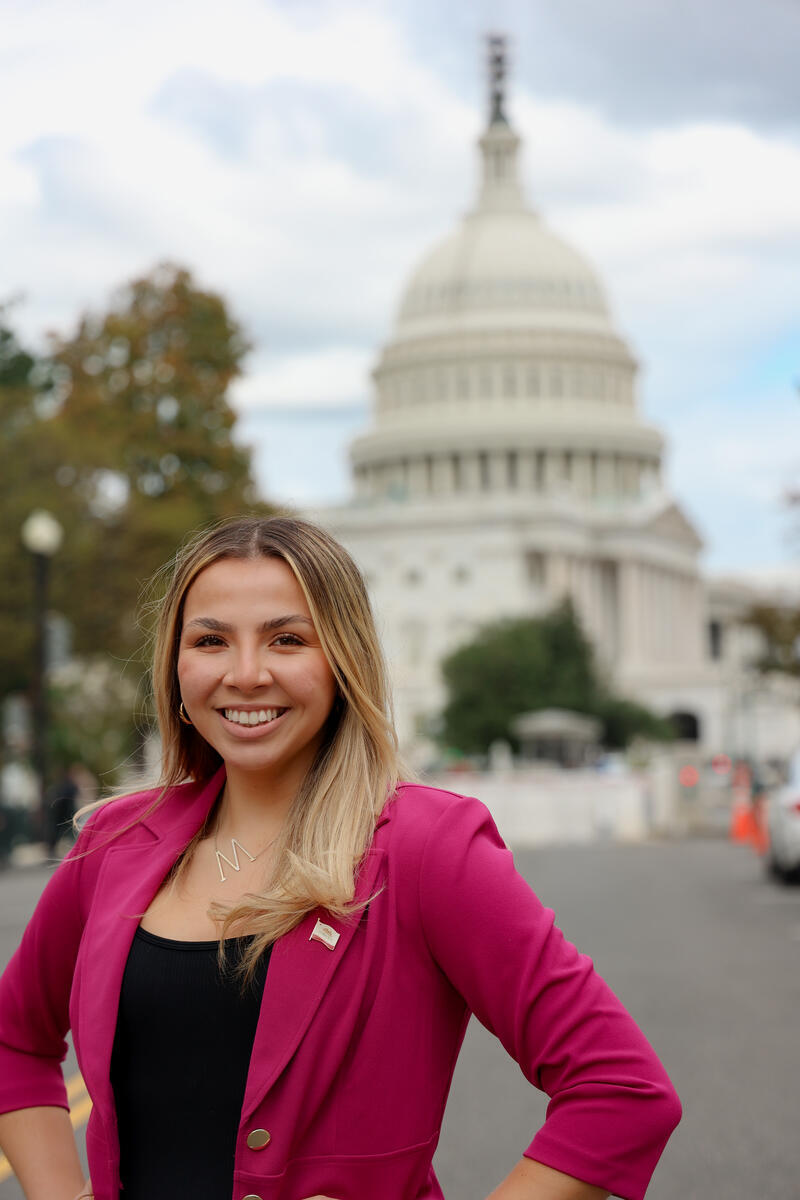 Woman standing in front of Capitol building in a magenta blazer and black top