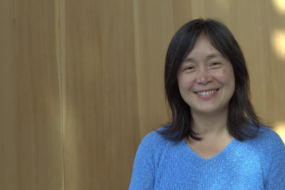 Woman with short dark hair, smiling, wearing a blue sweater