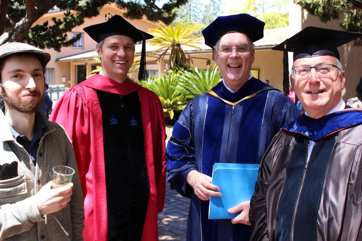 Group of professors standing together after the ceremony smiling.