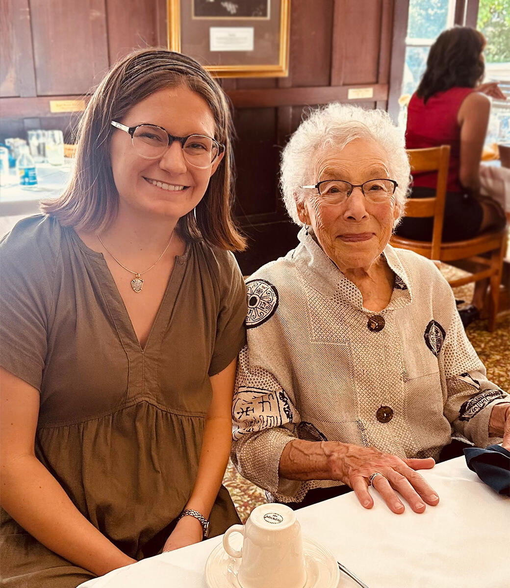 Two women wearing glasses smile while seated at a restaurant table