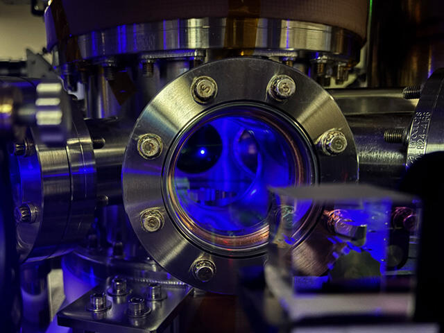 Through a glass window, a small dot is visible in a metal chamber