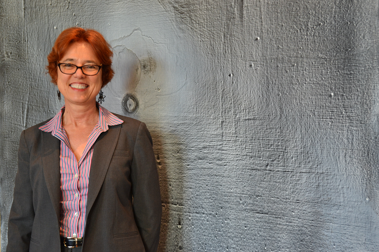 Professor posing in front of cement textured wall