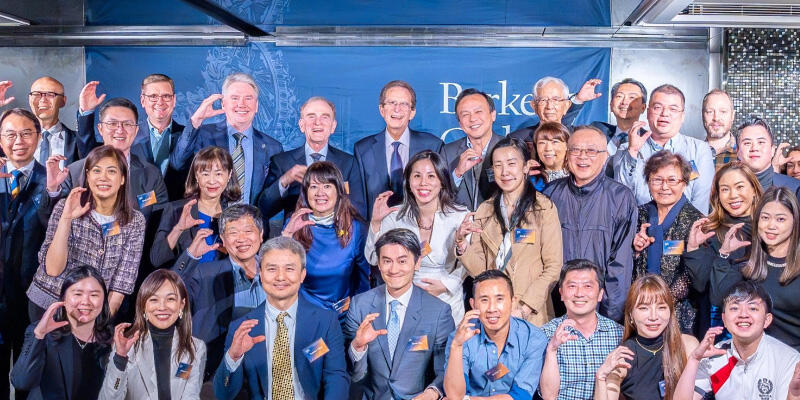 Michael Botchan (top row, center) is surrounded by dozens of Cal alums making "C" signs with their right hands