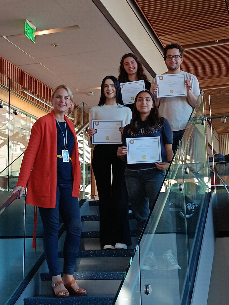 Julia Schaletzky and four students holding certificates pose on a staircase