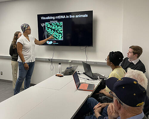 Professor Samantha C. Lewis explains her lab's research to visitors.