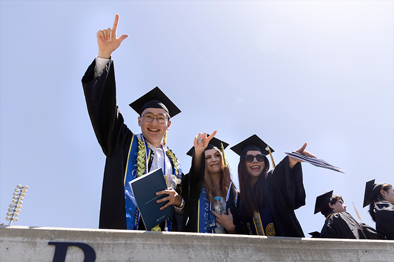 Graduates wave at camera