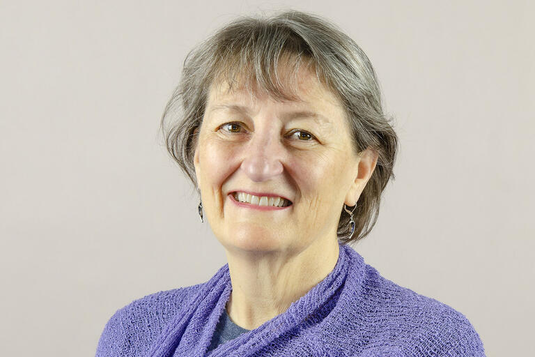 A headshot of a smiling woman in front of a plain background