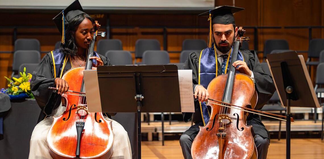 Two graduates perform string instruments at graduation