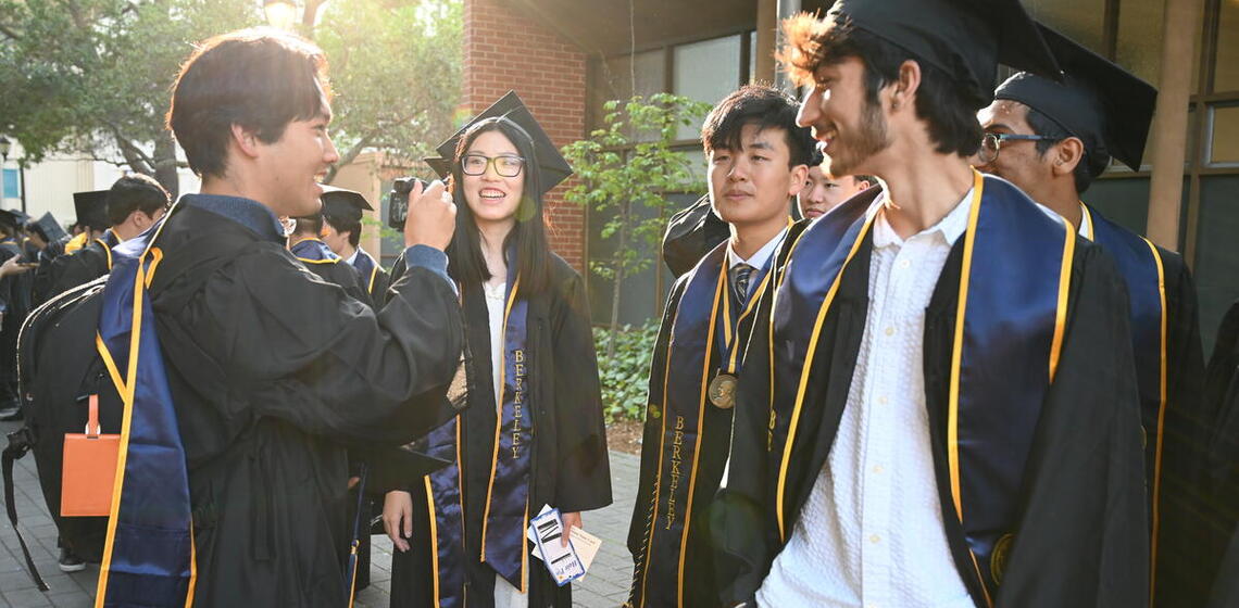 Group of graduates in regalia smile for a group photo