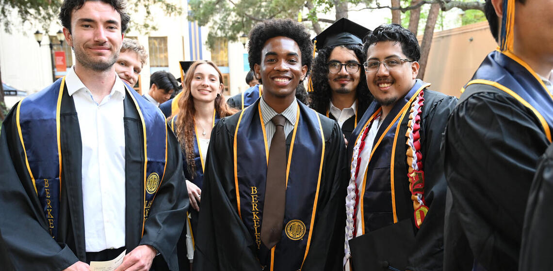 Group of graduates in regalia smile for a group photo