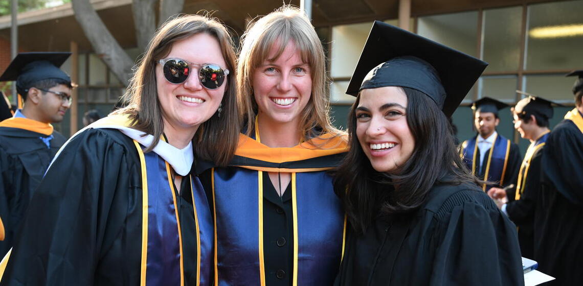 Group of graduates in regalia smile for a group photo