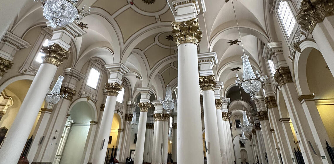 The ornate interior of a church features columns, arches, and chandeliers