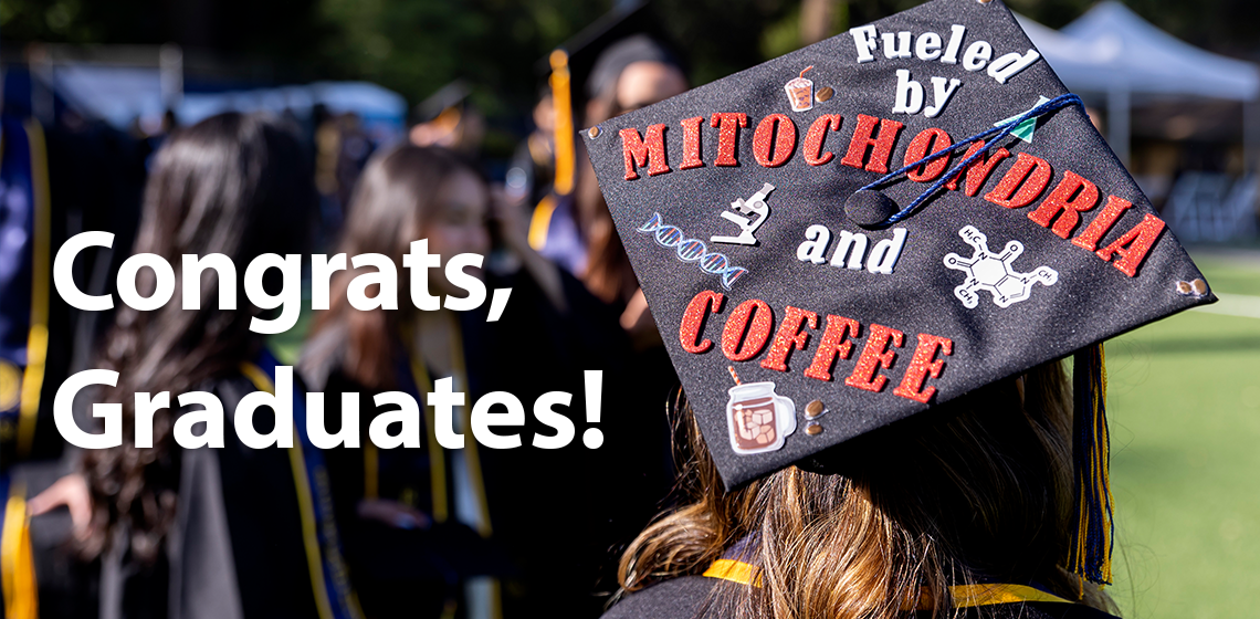 Back of graduation cap is decorated and says "Fueled by mitochondria and coffee" along with Congrats, Graduates!