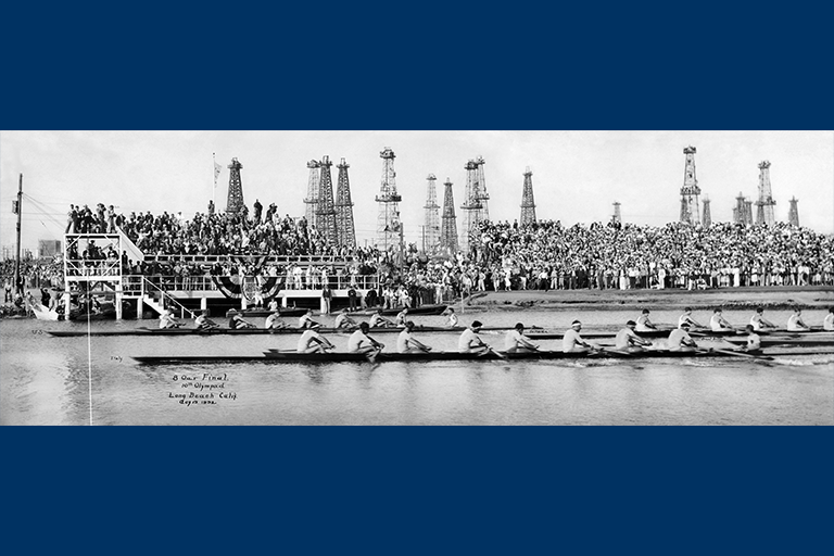 Black and white image of men rowing in front of a large crowd