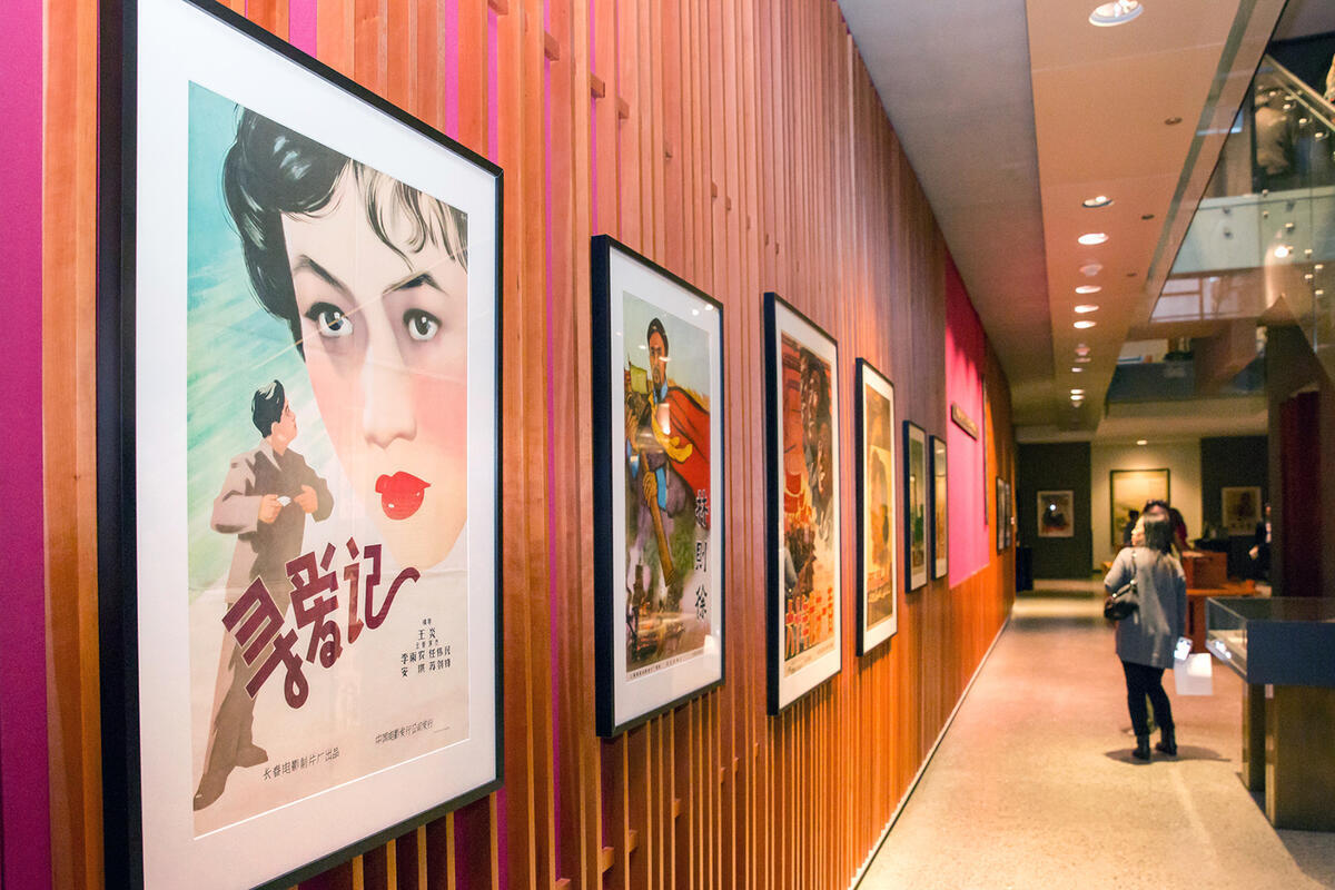 A visitor looks at items from the Paul Fonoroff collection hanging at the C. V. Starr East Asian Library at an event in 2017.