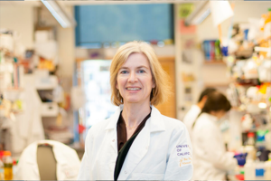 Jennifer Doudna wearing a white lab coat and standing in a lab